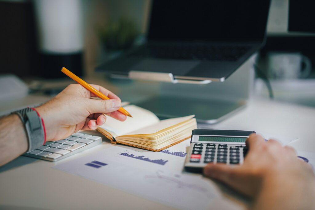 Taschenrechner und Notizbuch auf Schreibtisch – Expense Management im Büroalltag